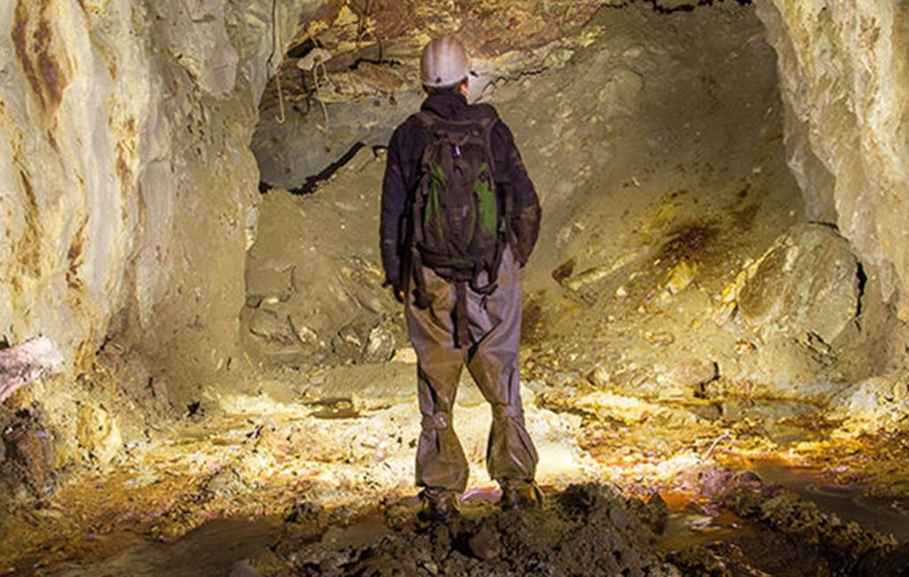 Abandoned copper ore mine underground tunnel with miner explorer Abandoned copper ore mine underground tunnel with miner explorer
